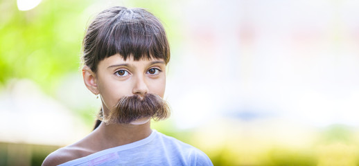 Young girl with fake mustaches hiding her smile. Dental health concept.