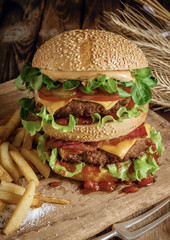 Delicious beef burger with chips and beer on wooden table.