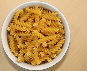 bowl of Fusilli pasta on wood background, copy space.