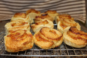 Freshly baked jam swirls cooling on a wire rack.