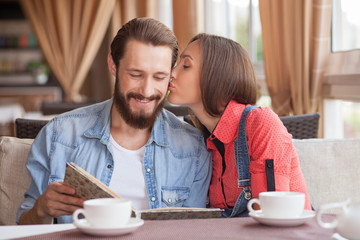 Cheerful young loving couple is dating in cafe