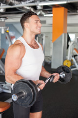 Cheerful young male athlete is exercising with barbell