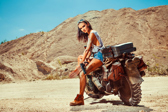 Sexy biker woman on the desert background.