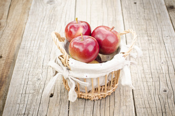 Apples in a basket on a wooden, grey background