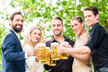 Freunde oder Kollegen im Biergarten zum Feierabend prosten sich zu