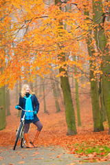 Happy active woman riding bike in autumn park.