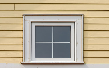 Small square window on a siding covered wall