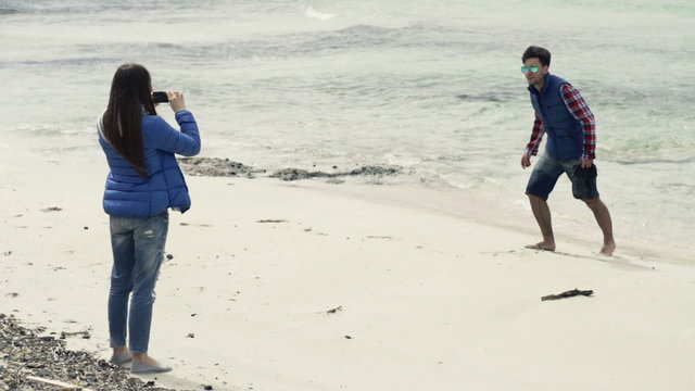 Girlfriend taking photo of her boyfriend on beach, slow motion shot at 240fps
