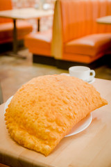 Beautiful large yellow colored empanada sitting on small white
