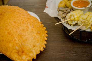 Delicious large empanada placed on white plate with other foods