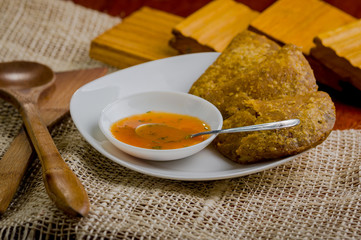 Three empanadas nicely arranged on white platter next to small