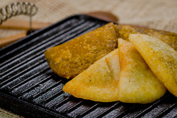 Closeup five empanadas lying in fan formation on black metal