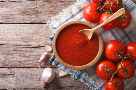 tomato sauce with garlic and basil in a wooden bowl. horizontal top view 
