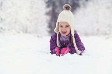 Fototapeta na wymiar Joyful child lies on the snow