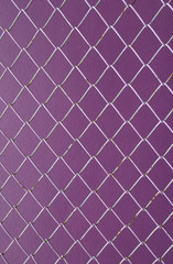 Fototapeta na wymiar Wire Mesh, iron wire fence on the wall purple background.