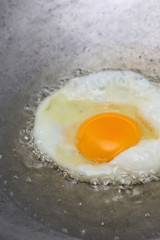cooking fried egg in hot pan with oil