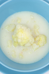 Blue bowl of cauliflower and potatoes soup.