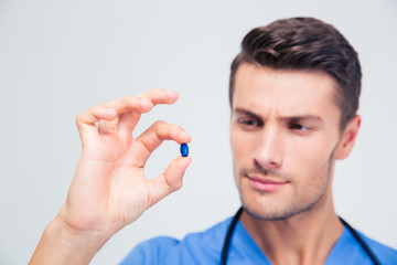 Fototapeta premium Portrait of a handsome male doctor holding pill