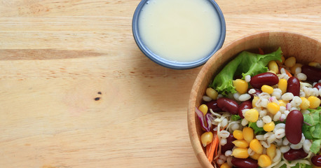 Healthy salad with fresh vegetables on wood background