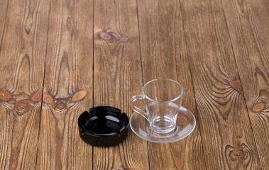 Empty cup with dish and ashtray on wooden texture