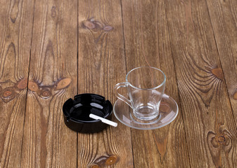 Cup with dish and cigarette in black ashtray