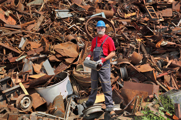 Recycling industry, worker stand at heap of old metal holding tube