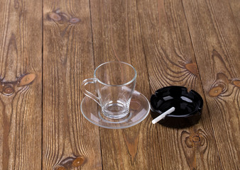 Cup with dish and cigarette in black ashtray