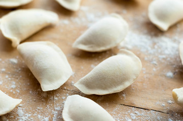 Fototapeta na wymiar Flat dumplings sprinkled with flour on wooden surface