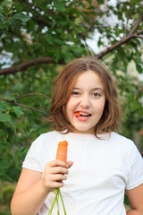 Adorable little girl with carrots in a garden