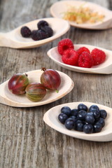 Different ripe berries in a wooden spoons