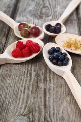 Different ripe berries in a wooden spoons