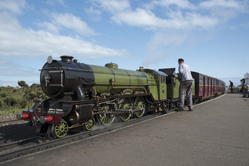 Engine driver polishing the Green Goddess loco which operates a passenger service between Hythe and Dungeness in Kent UK