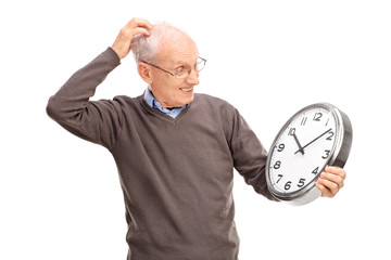 Confused senior holding a big wall clock