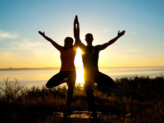 smiling couple making yoga exercises outdoors