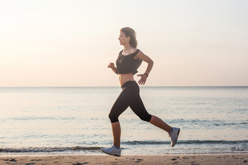 Fototapeta na wymiar Running woman. Female runner jogging during the sunrise on beach.