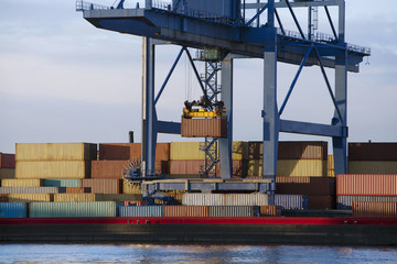 Gantry crane lifting a container from stack to a barge