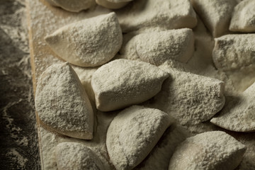homemade pasta ravioli over wooden table with flour. kitchen utensils