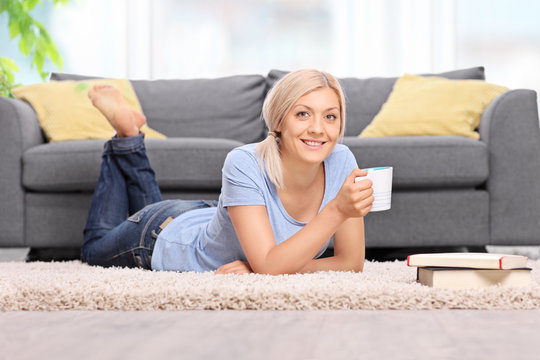Young woman drinking coffee and lying on the floor