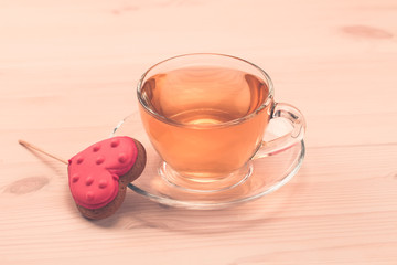delicious fresh cookies in the shape of a heart on a white plate on wooden background. A Cup of green tea.Breakfast