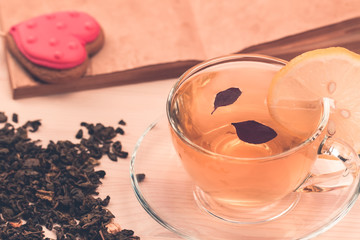 delicious fresh cookies in the shape of a heart on a white plate on wooden background. A Cup of green tea.Breakfast