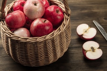 Basket of fresh ripe red apples on wooden background