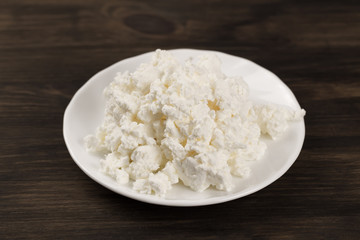 fresh tasty cottage cheese on a plate on wooden background. Homemade, curd