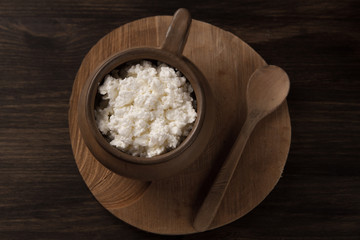 fresh tasty curd in pot on wooden background. Homemade, cottage cheese