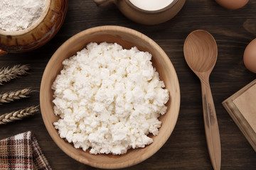 fresh tasty curd in pot on wooden background. Homemade, cottage cheese