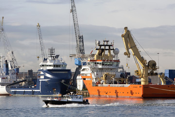 Two offshore supply ships moored in the harbor. A crewtender is passing by