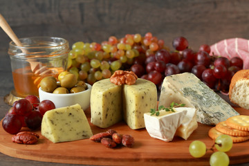 Glass of red wine with various types of cheese, fruits and appetizers