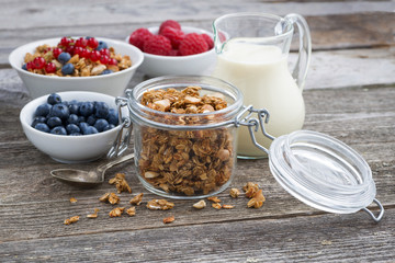 jar with granola, milk, and fresh berries on the wooden table