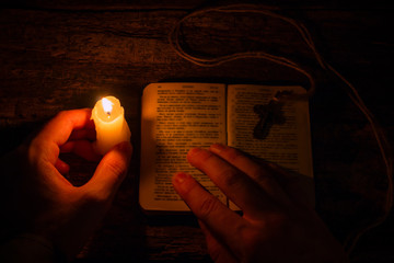 man praying on the Bible in the light candles selective focus