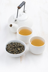 teapot and cups of green tea on a white wooden table, top view