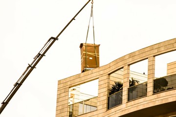 Fototapeta na wymiar Delivery of the refrigerator in original packaging to the penthouse via truck crane